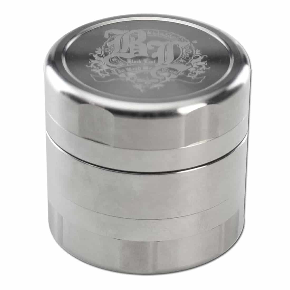 En sort, fem-delt krydderikværn i rustfrit stål præsenterer sig med en glat overflade og en mat finish. Kværnen har en rund form med en diameter på 49 mm. Den øverste del har en skruelås, mens den nederste del indeholder et fint gitter til opsamling af krydderier. Kværnen har små knopper til greb og et diskret logo.