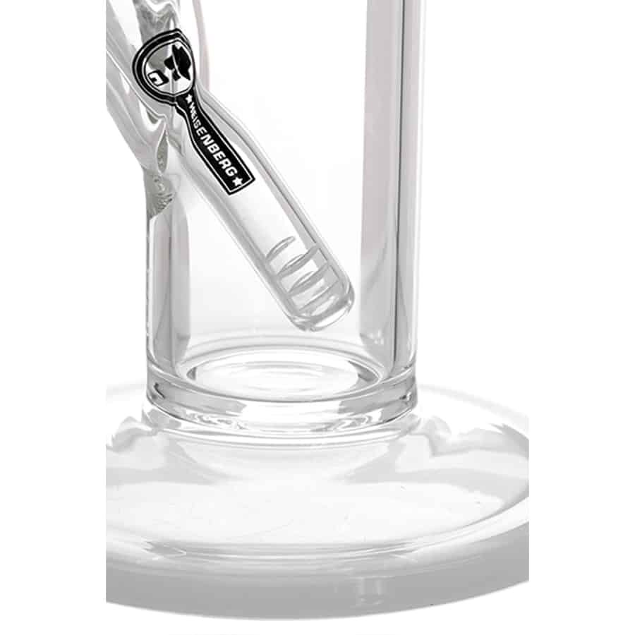 Den præsenterede perkolator har en glat, transparent krop i klart glas, der afslører den indvendige struktur. Den har en aflang, cylindrisk form med en bred åbning og en let buet top. Håndtaget er bølget og fremstår i sølvfarvet metal. En tæt, silikoneagtig pakning ses omkring åbningen, mens bunden har en specifik tekstur, der sikrer stabilitet.