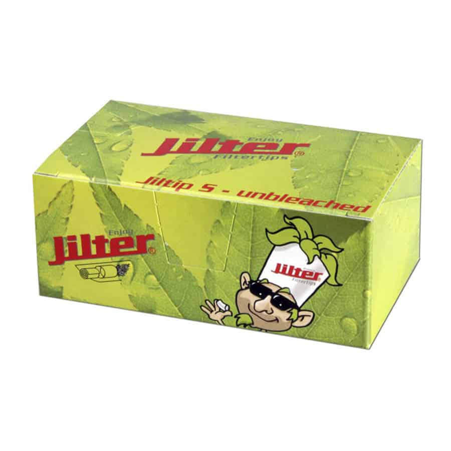 Jilter Jiltip filtertips præsenteres i en pakke med en naturlig, ubleget farve. Pakken har en rektangulær form og viser tekst i sort, der angiver produktets navn og egenskaber. Indholdet består af små cylinderformede filtertips med en let tekstureret overflade. De ligger stablet i en række, hvilket fremhæver deres ensartede størrelse og form.