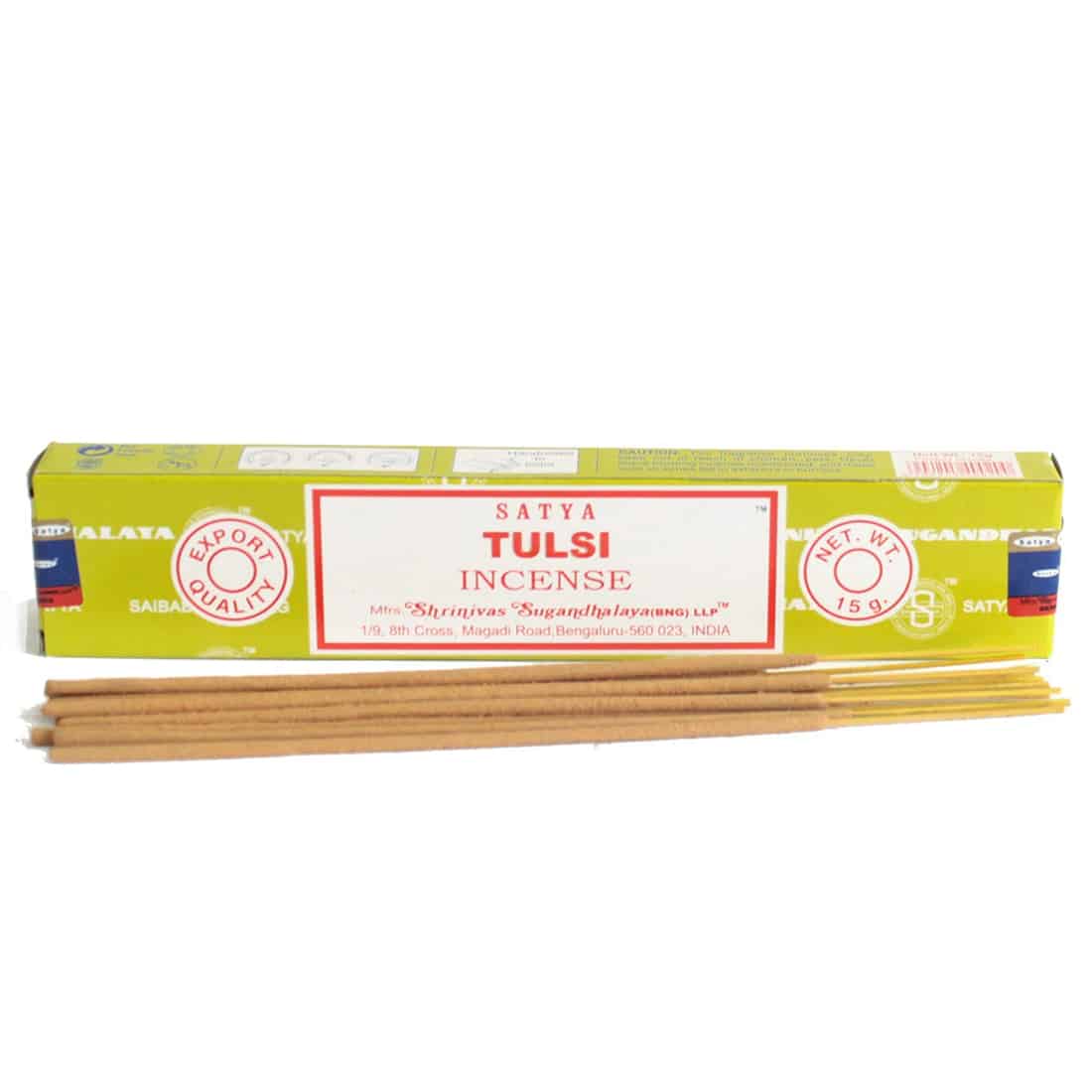 En pakke med røgelse præsenterer sig i en rektangulær form, dækket af en dyb lilla farve med gyldne detaljer. Fronten viser et stiliseret mønster og teksten "Satya Tulsi" i en elegant skrifttype. Den øverste del er prydet med små symboler, mens bunden er præget af en blød tekstur, der giver et luksuriøst indtryk.