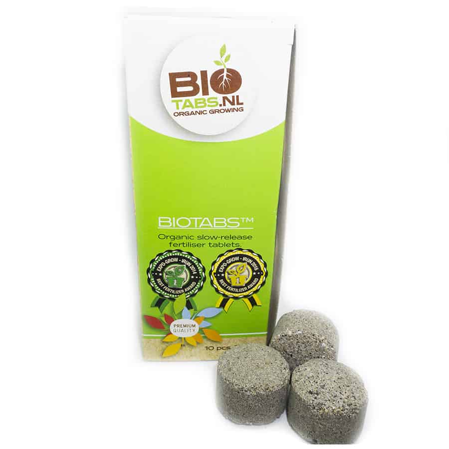 Ti tabletter præsenteres i en sort, genkendelig emballage med en mat overflade. Hver tablet har en rund form og en lys grå farve med små prikker, der indikerer en granularitet. Emballagen har en tydelig tekst, der angiver produktnavn og ingredienser i hvid skrift, samt et symbol, der indikerer, at produktet er naturligt.