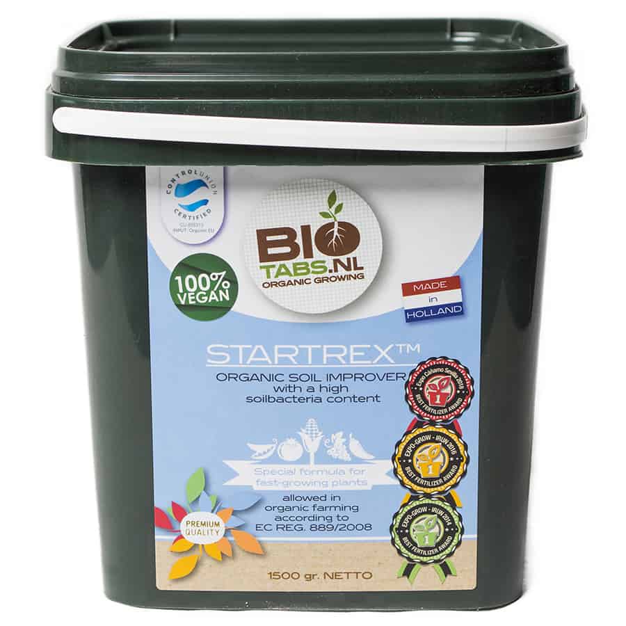 En hvid plastbeholder med en skruehætte præsenterer et indhold på 1500 gram. Etiketten er farverig med grønne, blå og orange nuancer, prydet med tekst og symboler, der angiver produktinformation. Beholderens overflade har en glat tekstur, mens etikettens skrift er tydelig og letlæselig. Indholdet synes at være granuleret, hvilket giver en struktureret fremtoning.