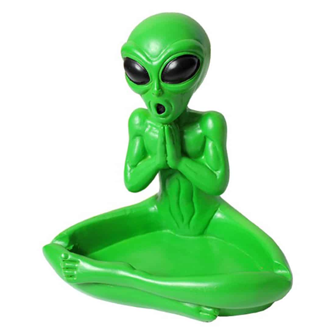 Et askebæger med en rund, skålformet struktur præsenterer sig i en skarp grøn farve. Overfladen har en glat, blank finish, der reflekterer lys. Det har et design med en stiliseret alien-lignende figur, hvor ansigtstræk er indgraveret i materialet. Bunden er flad, og askebægeret har en lille kant, der adskiller det fra underlaget.