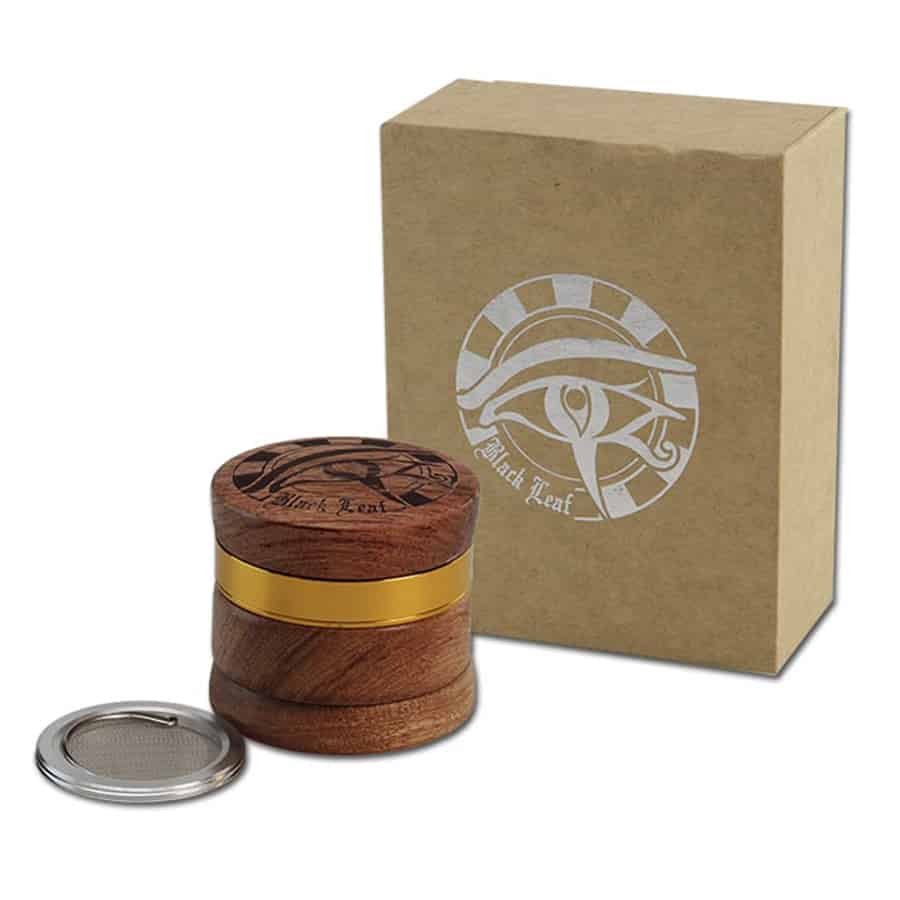 En sort, bladformet kværn fremstillet af egyptisk træ pryder overfladen med en glat, mørk finish. Kværnen har en let buet form og fremstår elegant med fine, naturlige åretegninger. Den er udstyret med en drejeknap, der er placeret centralt, og har et minimalistisk design, der fremhæver træets strukturelle skønhed.