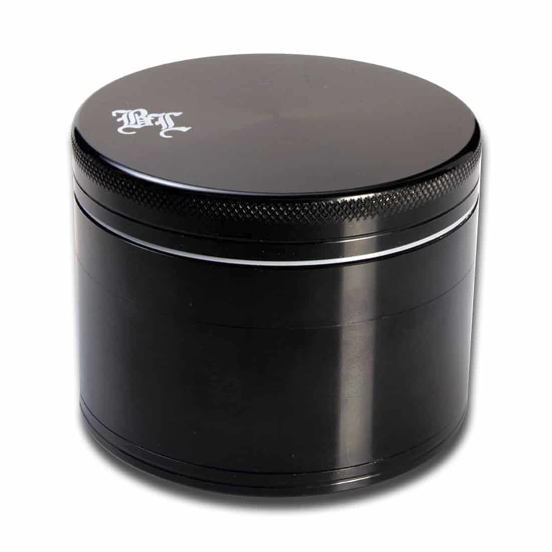 En sort urteknuser med en diameter på 75 mm præsenterer et glat, mat ydre med en let skridsikker overflade. Toppen har en flad, cirkulær form og er udstyret med små, fine tænder til formaling. Den nederste del indeholder et skuffesystem til opsamling af det knuste materiale, og en diskret, grå metalrefleksion kan ses indeni.