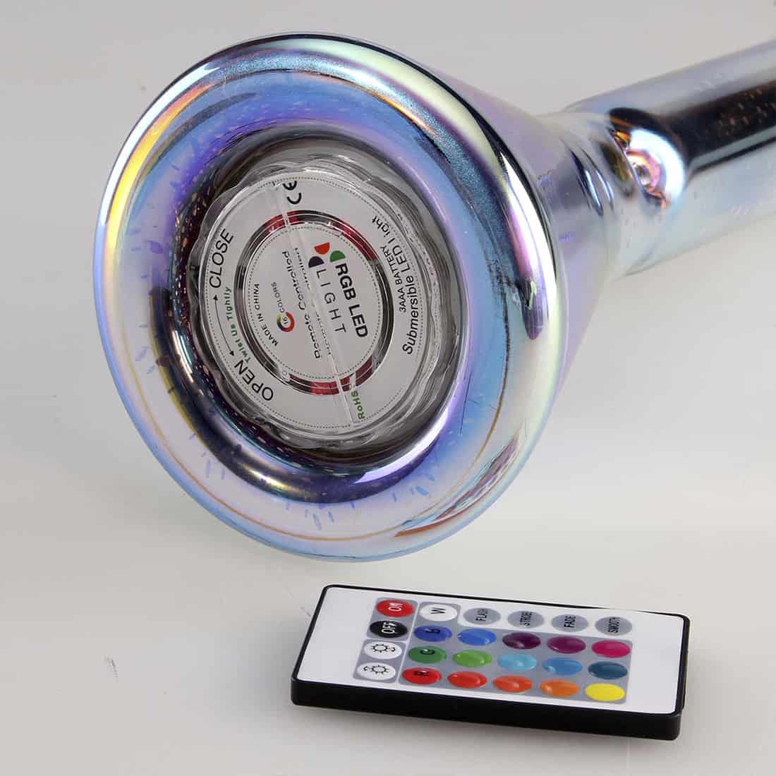 En transparent bong med en slank, cylindrisk form, der strækker sig 35 cm opad. Overfladen prydes af et farverigt, bølgende mønster i nuancer af blå, grøn og orange, der skaber en dynamisk visuel effekt. Toppen er forsynet med en bred åbning, og bunden har en stabil cirkulær fod. En LED-lampe er indbygget, som leverer lys til bunden.