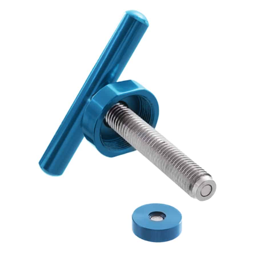 En poleret, blå top i aluminium præger designet med en glat, reflekterende overflade. Den er firkantet og har afrundede kanter, hvilket giver et moderne udtryk. Understøttende ben i metal er synlige, og der er små, sorte gummifødder for stabilitet. En enkelt, diskret knap sidder på fronten, der tilføjer en funktionel detalje til det samlede udseende.