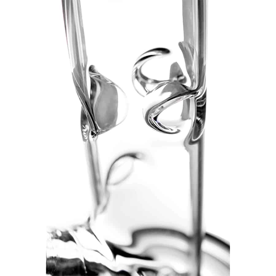 En sort, cylindrisk brænder med en glat overflade og en blank finish dominerer. Den har en afrundet top og en solid bund, der giver stabilitet. På siden findes en lille, rund knap med et mærke, der indikerer regulering af flammen. Materialet ser robust og holdbart ud, med en elegant og moderne formgivning.