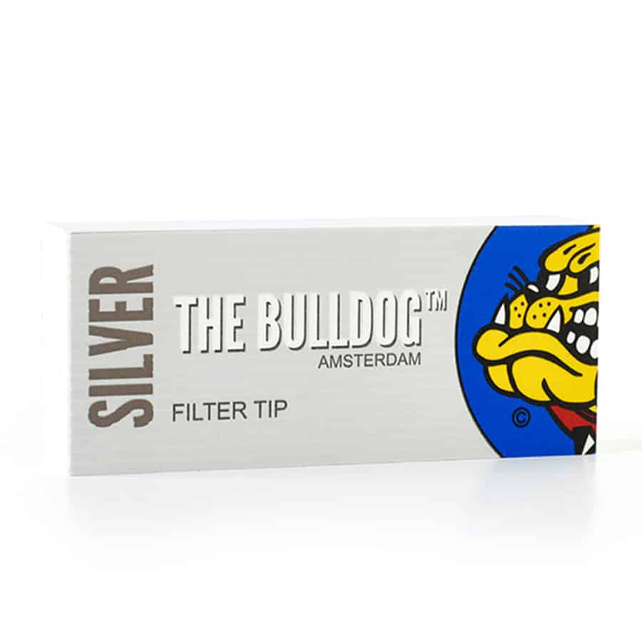 Sølvfarvede filtertips præsenteres i en rektangulær pakke med en glat, metallisk overflade. Designet har en enkel, minimalistisk æstetik med sorte skrifttyper, der angiver produktets navn og specifikationer. Pakken er lukket med en foldelukning, og indholdet består af en række ensartede filtertips med en let tekstureret overflade, der er synlige gennem åbningen.
