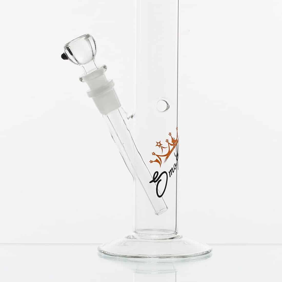 En bongs cylindriske krop er fremstillet af klart glas, der afslører indvendige rør og kamre. Den øverste del har en rund, åben krave, mens bunden er bred og stabil. Farverne inkluderer nuancer af grøn og blå, med et glinsende finish. Den er prydet med en dekorativ, farverig perle ved halsen og en skål til tobaksprodukter.