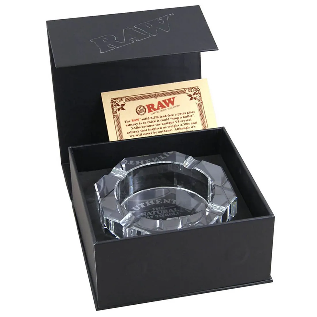 Et askebæger i klar, transparent krystal med en glat overflade og en skarp kant. Det har en rund form med en let hævet midte, der skaber en dybde. Bunden er flad og robust, hvilket giver stabilitet. Lys reflekteres smukt i krystallet, hvilket skaber en glitrende effekt, mens indvendige detaljer fremhæver materialets klarhed.