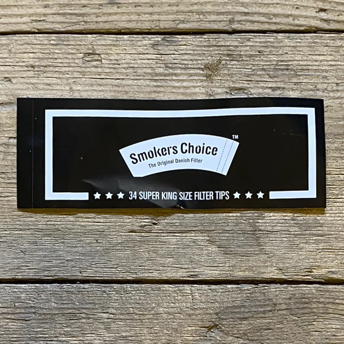 Klistermærket har en sort baggrund med en glat tekstur. I midten står teksten "Smokers Choice" i en fremtrædende, hvid skrifttype. Omkring teksten er der en tynd, hvid kant, der fremhæver logoet. Klistermærket har en oval form, hvilket giver det et kompakt udseende, der er let at påføre.