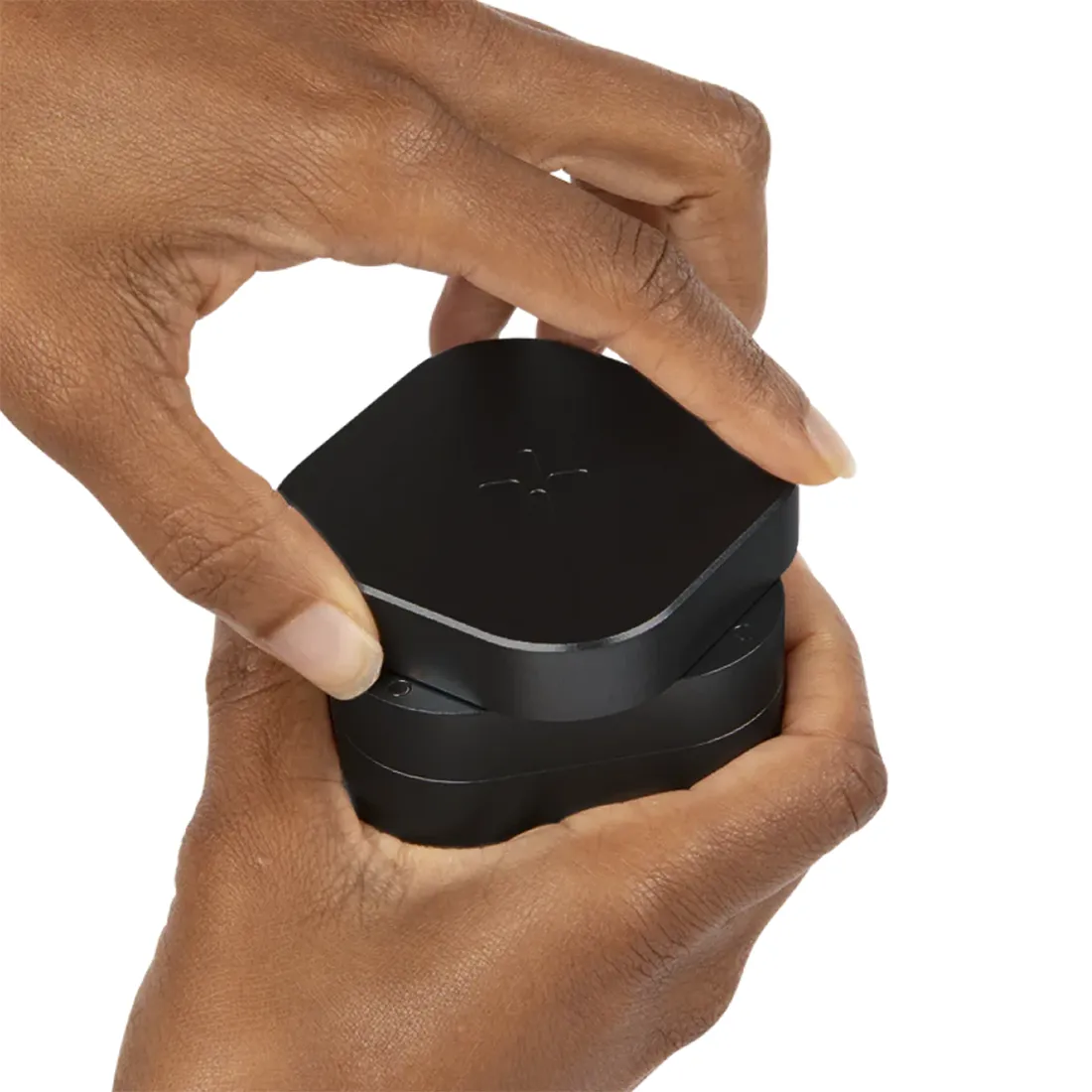 En sort kaffekværn med en slank, cylindrisk form præget af et mat finish. Den øverste del har en rund, skridsikker knap i metal med en børstet overflade. Kværnens side er mærket med en minimalistisk logo i hvid, mens bunden har en let skrællede tekstur. Kværnen har en praktisk, kompakt størrelse, ideel til køkkenbrug.