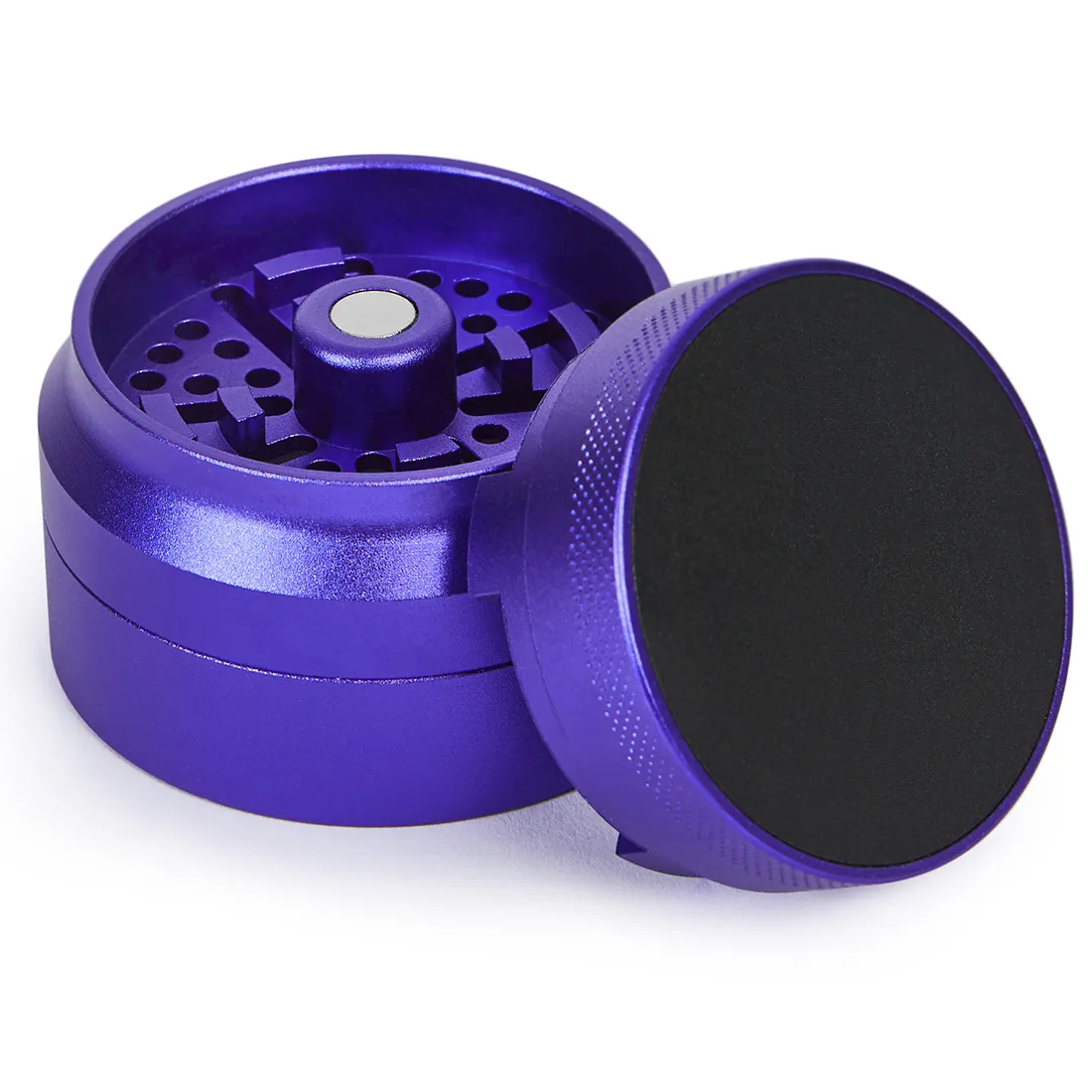 En lilla krydderkværn med en glat, blank overflade pryder midten. Den har en cylindrisk form med en diameter på 55-63 mm. Kværnen er opdelt i flere sektioner, der inkluderer en top med skridsikkert greb og små, skarpe tænder indeni. Nederst findes en skruelåg med indgraverede mønstre, der giver et dekorativt præg.