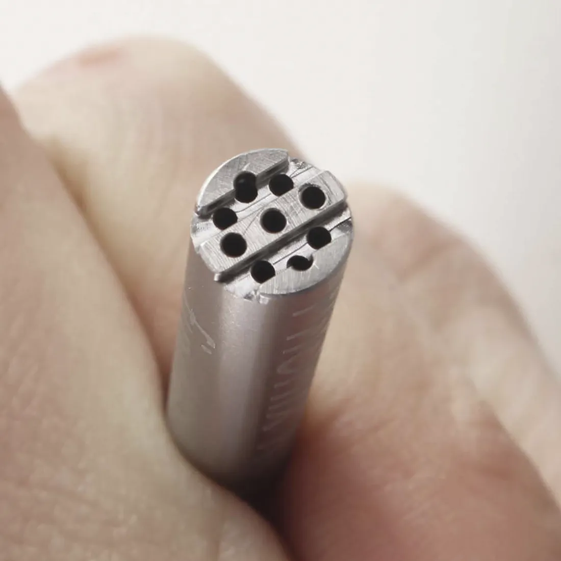 Aktiv kulfiltertips fremstår i rustfrit stål med en blank overflade, der reflekterer lys. De har en cylindrisk form med afrundede kanter. Overfladen er glat, og der er fine, subtile mønstre, der tilføjer tekstur. Filtertipsene er placeret i en praktisk holder, der også er i rustfrit stål, hvilket skaber en ensartet æstetik.