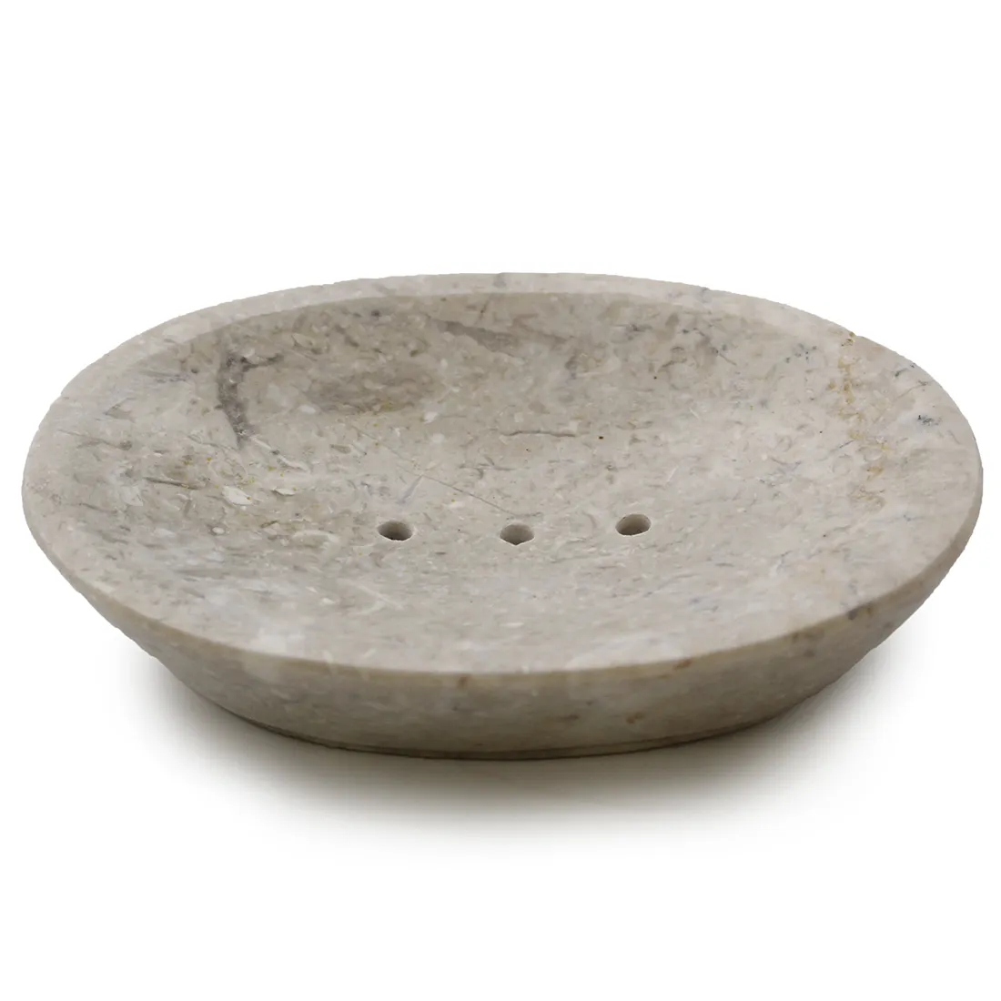 En oval sæbeskål i cremefarvet keramik præsenterer sig med en glat, ensartet overflade. Skålen har let hævede kanter, der skaber en elegant form. Den matte tekstur giver et subtilt udtryk, mens skålens bund er flad, hvilket sikrer stabilitet. En diskret, rund afløbsåbning er placeret i midten, hvilket tilføjer funktionalitet til designet.