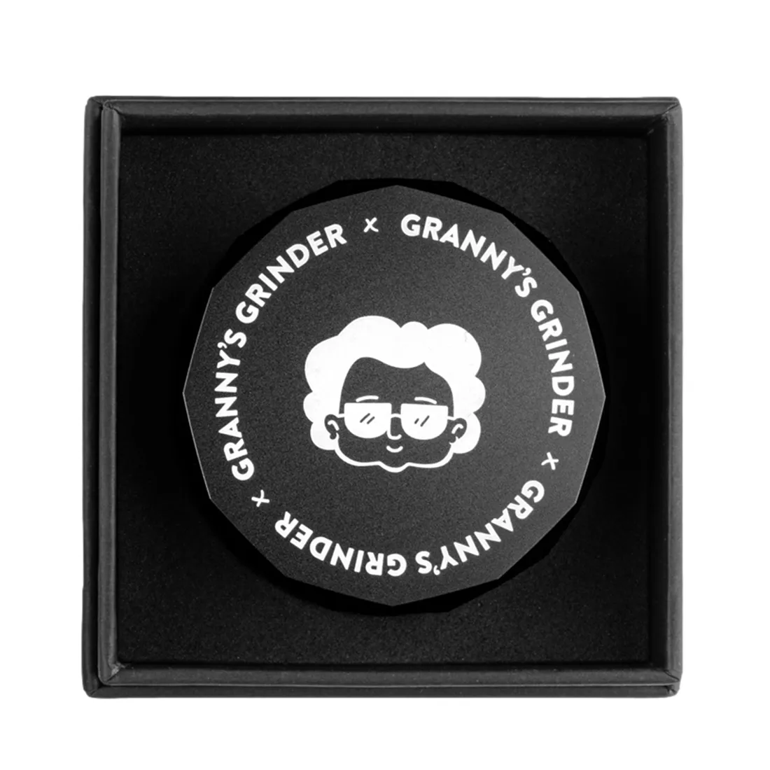 En sort hexagonal grinder med en diameter på 55 mm. Overfladen er mat og ensartet, uden synlige reflekser. Kanten er let afrundet, hvilket giver en blødere profil. Der er indgraverede linjer langs kanten, der skaber et geometrisk mønster. Grinderens indre har skarpe tænder, der er synlige, og en fin struktur, der sikrer effektiv kværning.