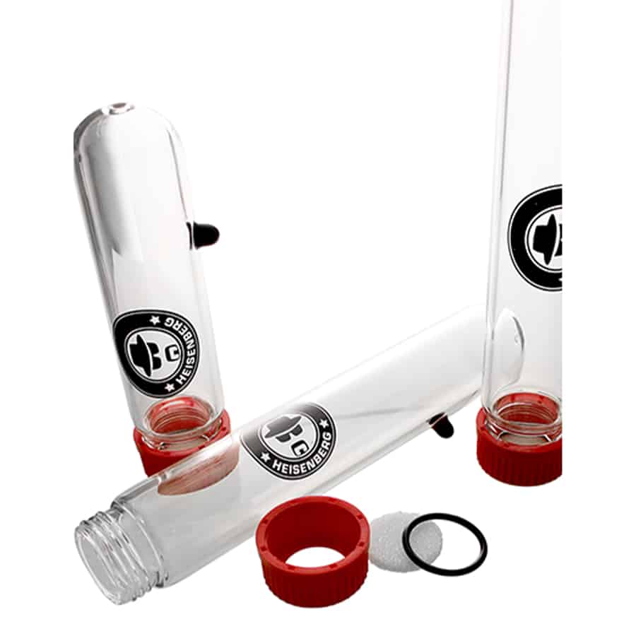 Heisenberg olieekstraktoren består af flere komponenter i klart glas og rustfrit stål. Den har en cylindrisk beholder med en bred åbning og en smal udløbsventil. Sammenkoblinger er synlige, med skruelåg og tætningsringe. Der er også en sil, der adskiller væske fra faste stoffer. Overfladerne er glatte med skarpe kanter, og der er tydelige markerede målelinjer på glasset.